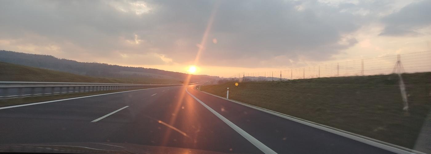 Pohľad z auta na diaľnicu a zapadajúce slnko počas cesty Nemeckom.