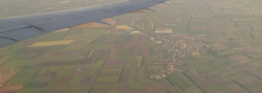 Výhľad z okna lietadla na zelené luky v okolí letiska Schwechat