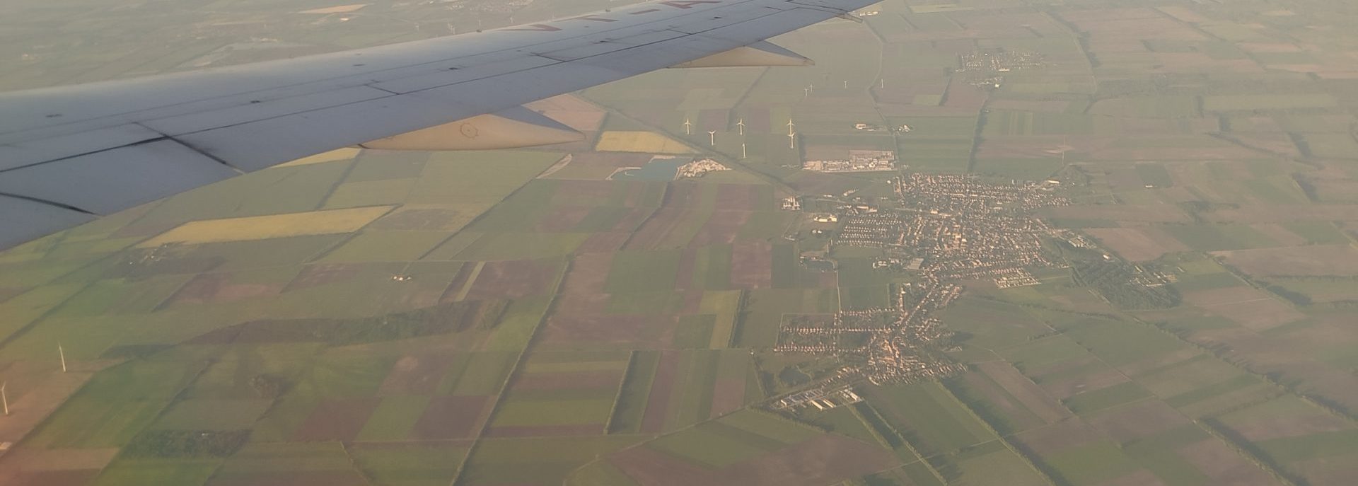 Výhľad z okna lietadla na zelené luky v okolí letiska Schwechat